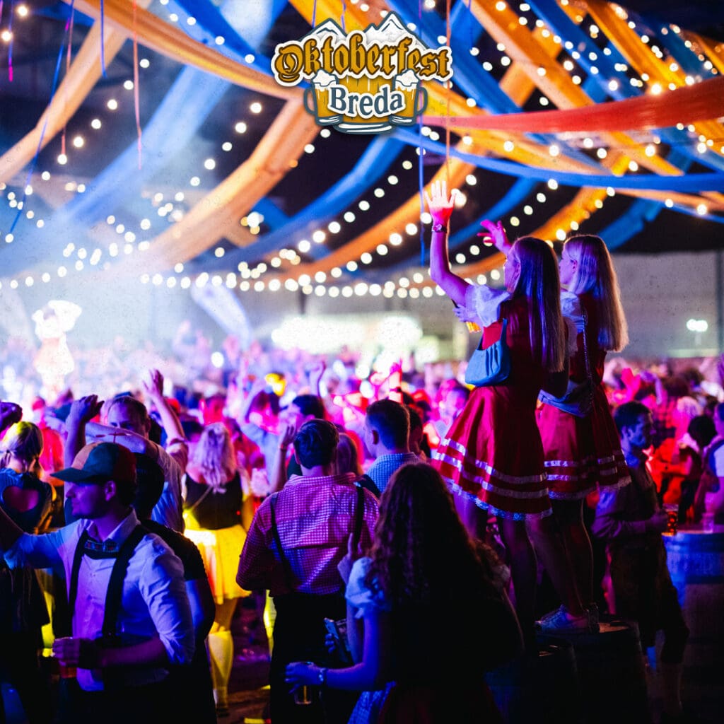 Oktoberfest breda vrienden aan een lange biertafel in de evenementenhal van Breepark.